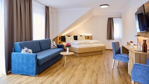 Une chambre d’hôtel moderne équipée d’un canapé, d’une petite table ronde, d’un lit et d’un espace bureau.