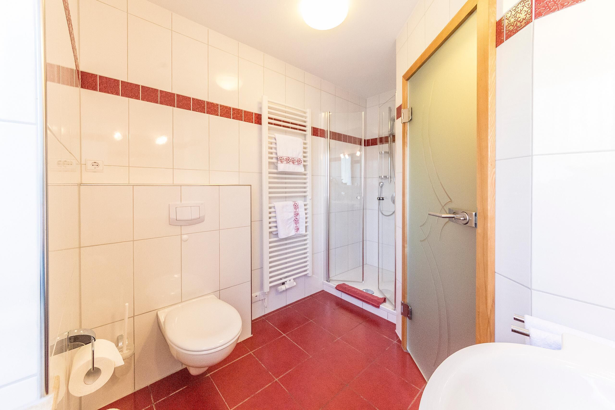 A bathroom with a toilet, a shower, and a glass-enclosed shower stall.