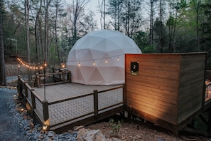 A dome-shaped tent with a wooden deck and a small wooden building with a number sign. - Glamp Blue Ridge - Dome 2 Brunson (Gilmer County)
