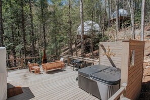 Una terraza de madera con mobiliario exterior, un jacuzzi y una parrilla.