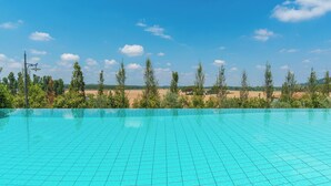 Ein Pool mit gefliestem Becken, umgeben von Bäumen und blauem Himmel.