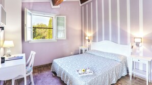 Ein Schlafzimmer mit Bett, Schreibtisch, Stuhl, Fenster und Deckenventilator.