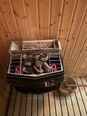 Un sauna doté d’un panneau de commande, d’une grille métallique et d’un plancher en bois.