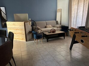 Un salon avec un canapé, une table basse et un baby-foot.