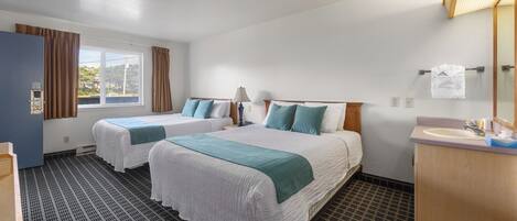 Habitación de hotel con dos camas, baño y ventana con cortinas.