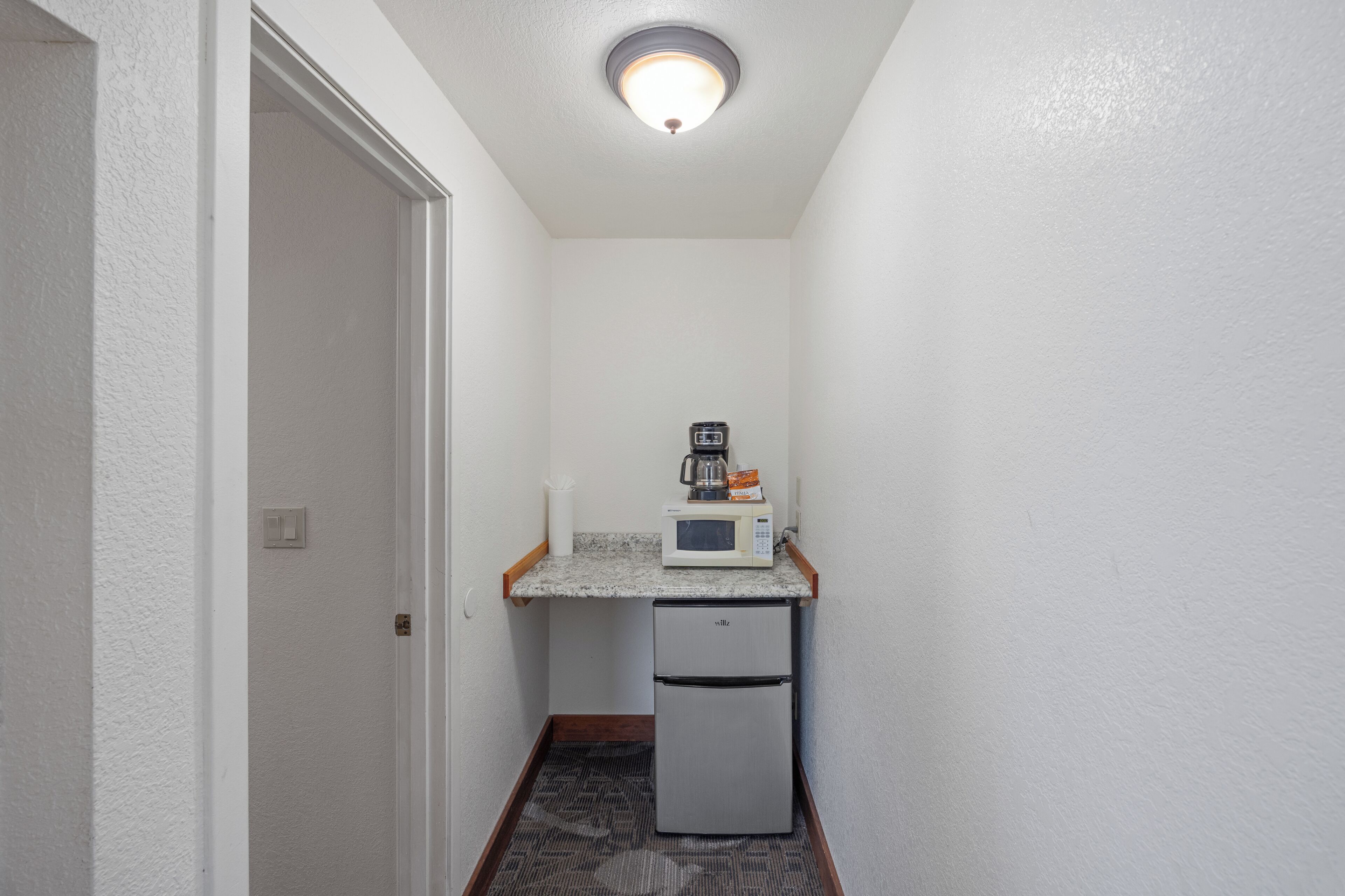 A small kitchenette with a microwave, a coffee maker, and a refrigerator.
