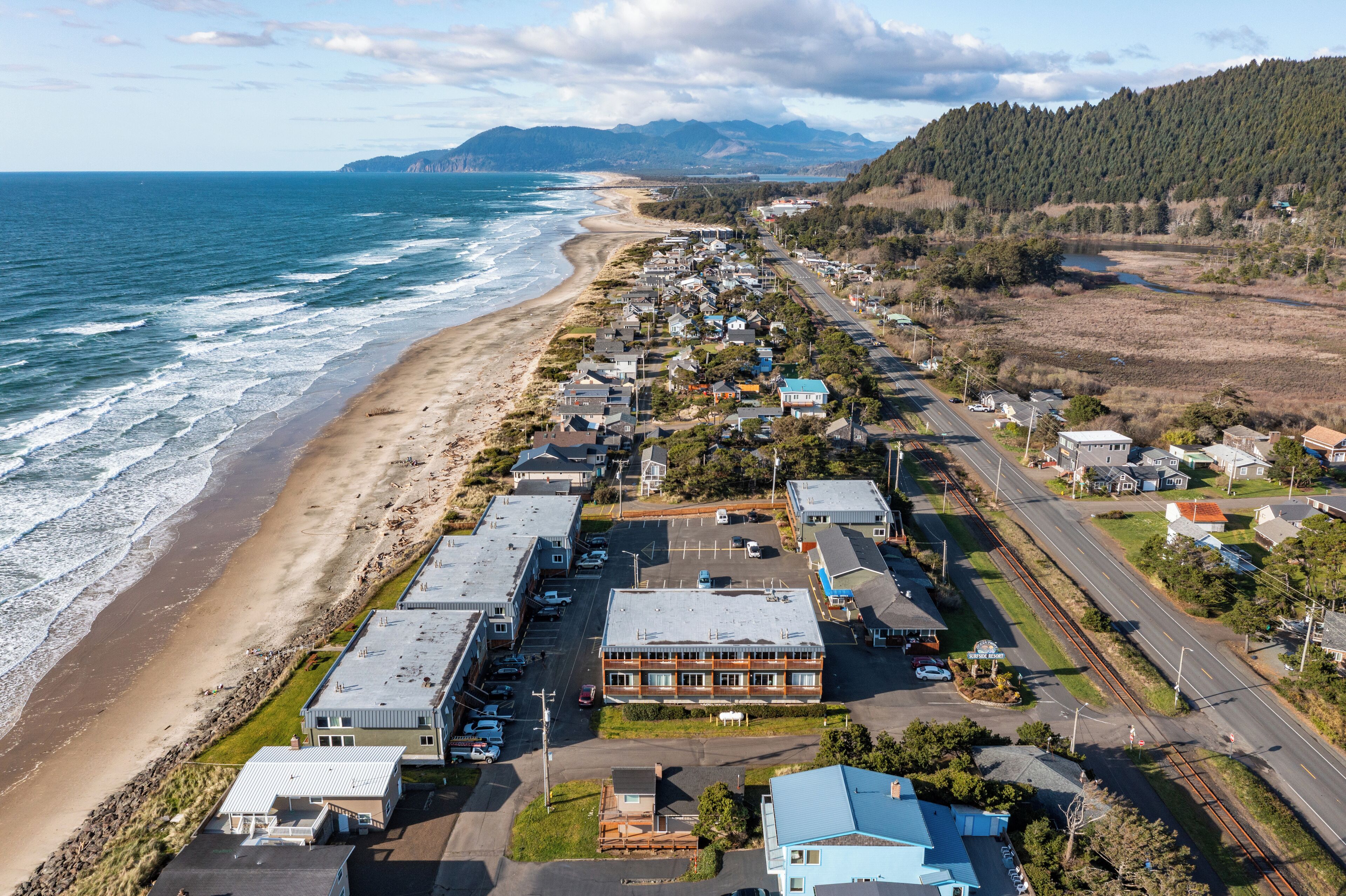 Un pueblo costero con playa, edificios residenciales y una carretera.