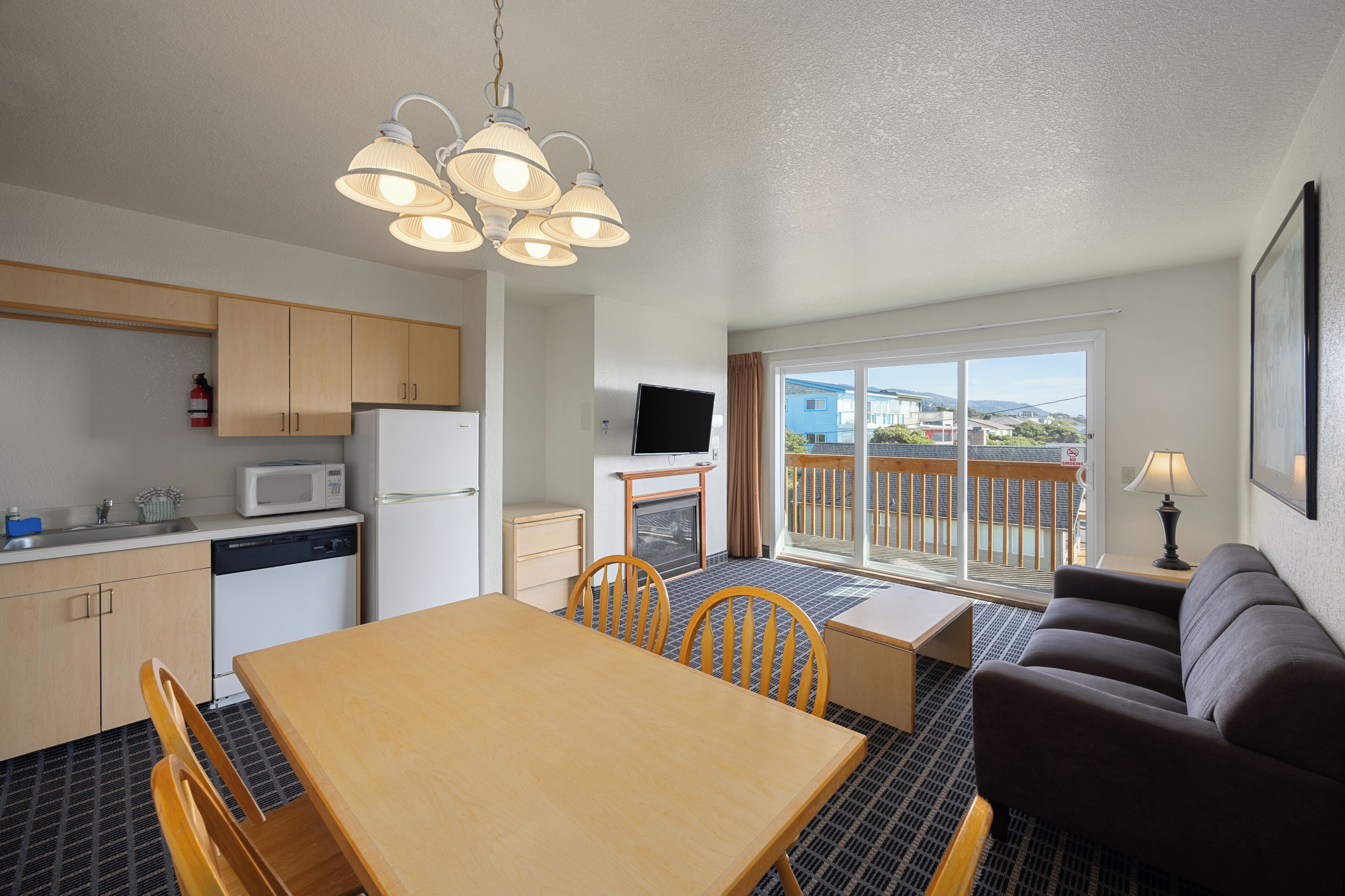A compact living space with a kitchenette, dining area, and a balcony with a view.