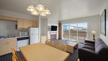 A compact living space with a kitchenette, dining area, and a balcony with a view.
