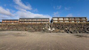 Ein Strandhotel mit mehreren Balkonen, einer felsigen Küstenlinie und einem klaren Himmel.