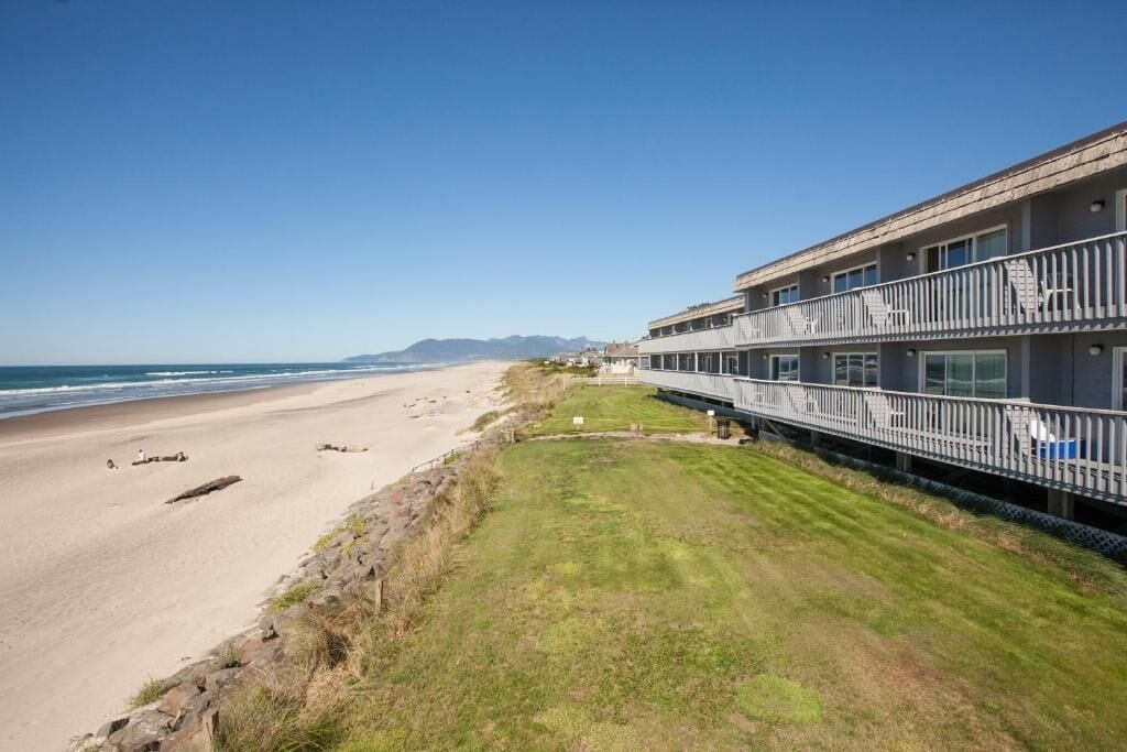 Un hôtel situé en bord de mer, doté d’un long balcon, d’une plage de sable et offrant une vue dégagée sur l’océan.
