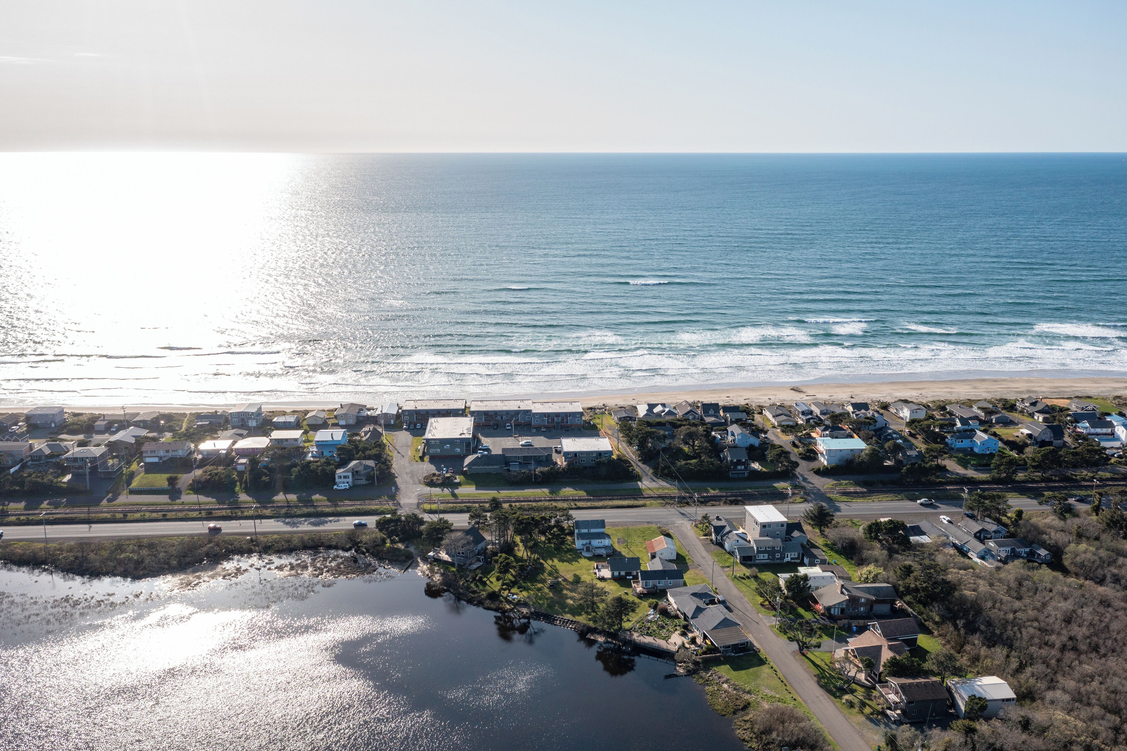 An aerial view of a coastal residential area with houses, a beach, and a body of water.