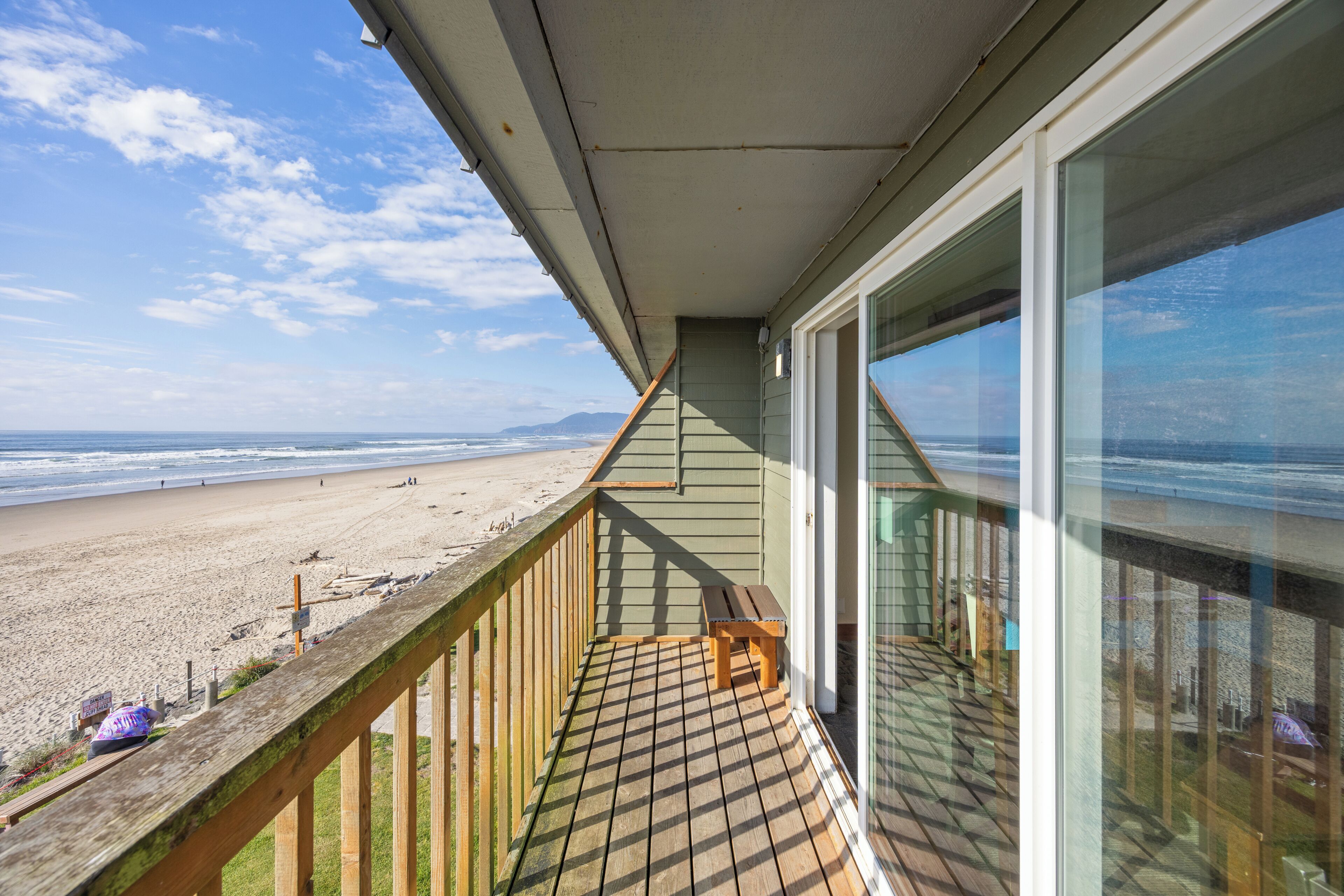 A wooden deck with a view of the beach and ocean.