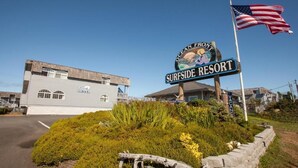 Ein Gebäude mit der Aufschrift 'Ocean Front Surfside Resort', das ein Schild mit einem Surfer und einer Strandansicht zeigt.