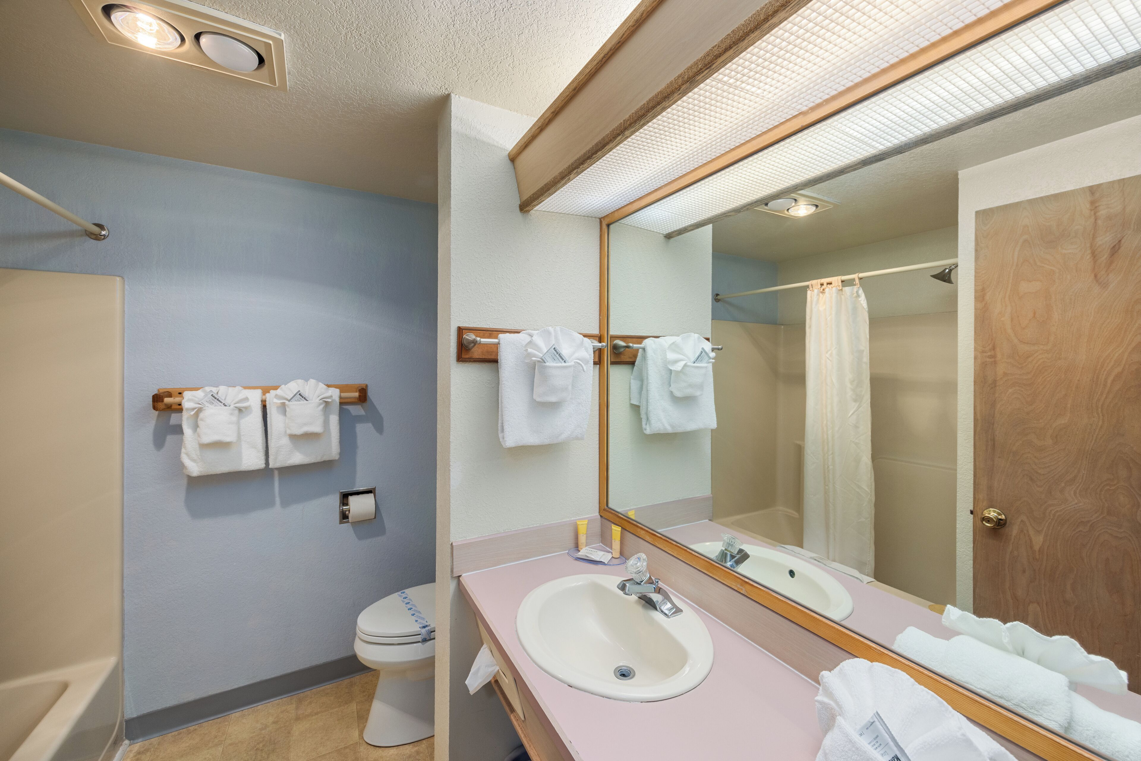 A bathroom with a toilet, sink, mirror, and towel rack.