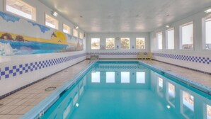 Ein Hallenbad mit gefliesten Wänden, Fenstern und einem Wandgemälde.