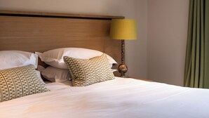 Una cama bien hecha con almohadas, un cabecero de madera y una lámpara.