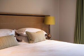 Una cama bien hecha con almohadas, un cabecero de madera y una lámpara.