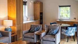 Una cocina moderna con armarios de madera, un comedor con sillas estampadas y un ventanal con vistas a la vegetación.