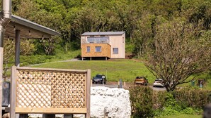 Ein modernes Haus mit Satteldach, einer Solaranlage und Blick auf einen grünen Hügel.