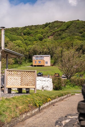 A modern house with a sloped roof, a solar panel, and a view of a green hill.