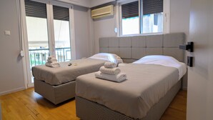 A hotel room with two beds, a balcony, and an air conditioning unit.