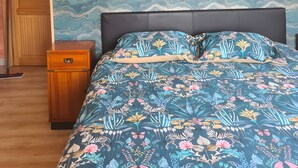 A bedroom with a patterned wall, a bed with floral bedding, two wall-mounted lamps, and a wooden nightstand.