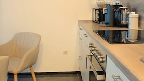 Une petite cuisine équipée d’une horloge murale, d’une machine à café et d’une chaise.