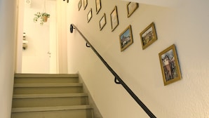 Un escalier muni d’une rampe, une porte en haut et plusieurs tableaux encadrés accrochés au mur.