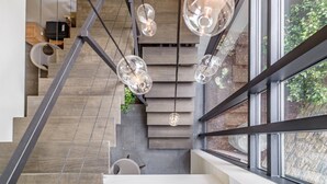 Eine moderne Treppe mit Glastrennwand, Pendelleuchten und Blick ins Grüne.