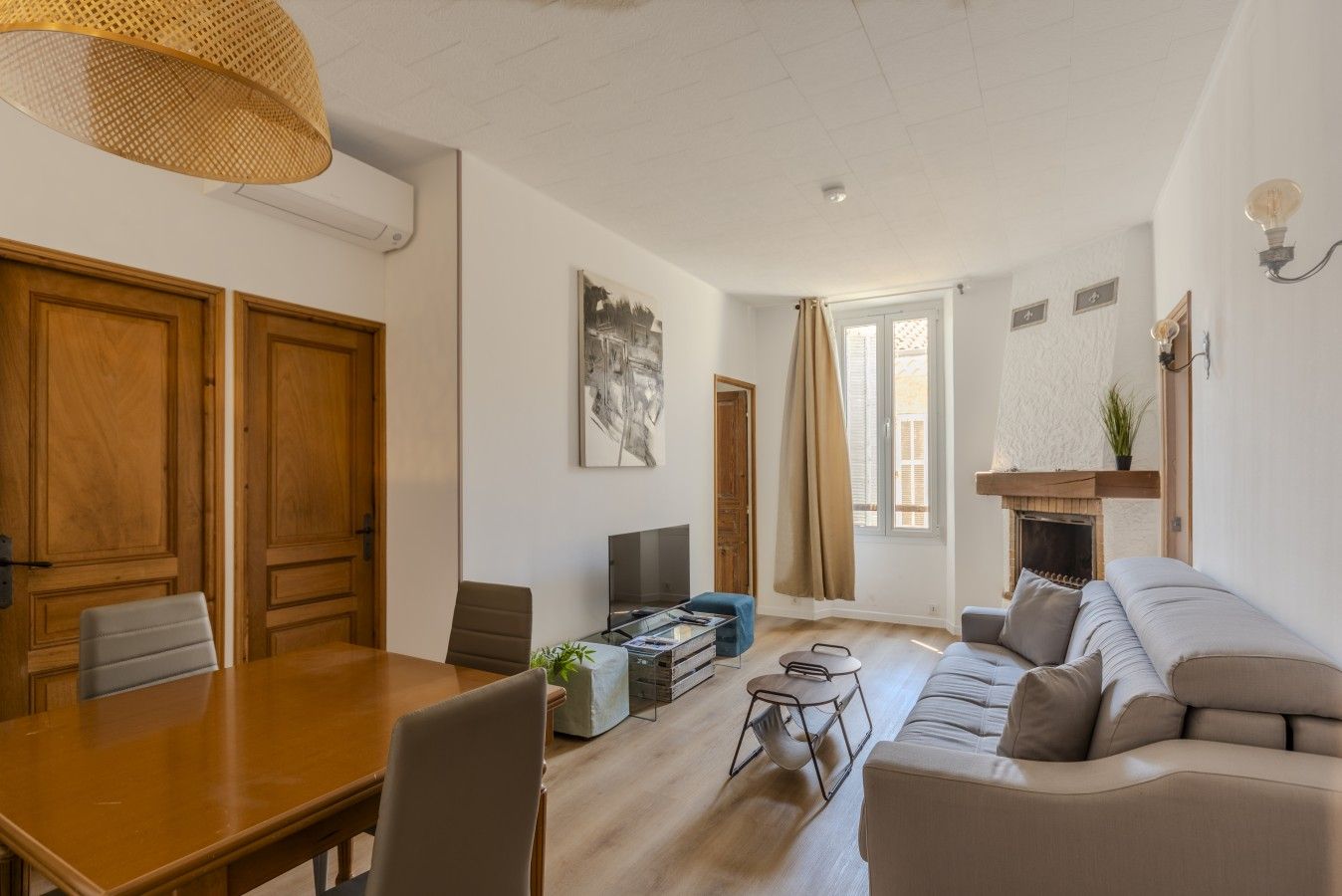 Amplia sala de estar con una mesa de comedor de madera, un sofá, un televisor y una chimenea.