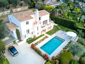 Ein modernes, zweistöckiges Haus mit Swimmingpool, einem Auto auf der Auffahrt und gepflegten Gärten.