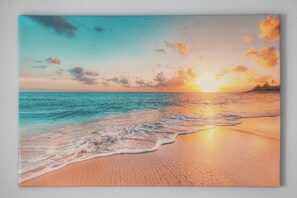 Eine Strandlandschaft mit Sonnenuntergang, Meereswellen und einer entfernten Küste.