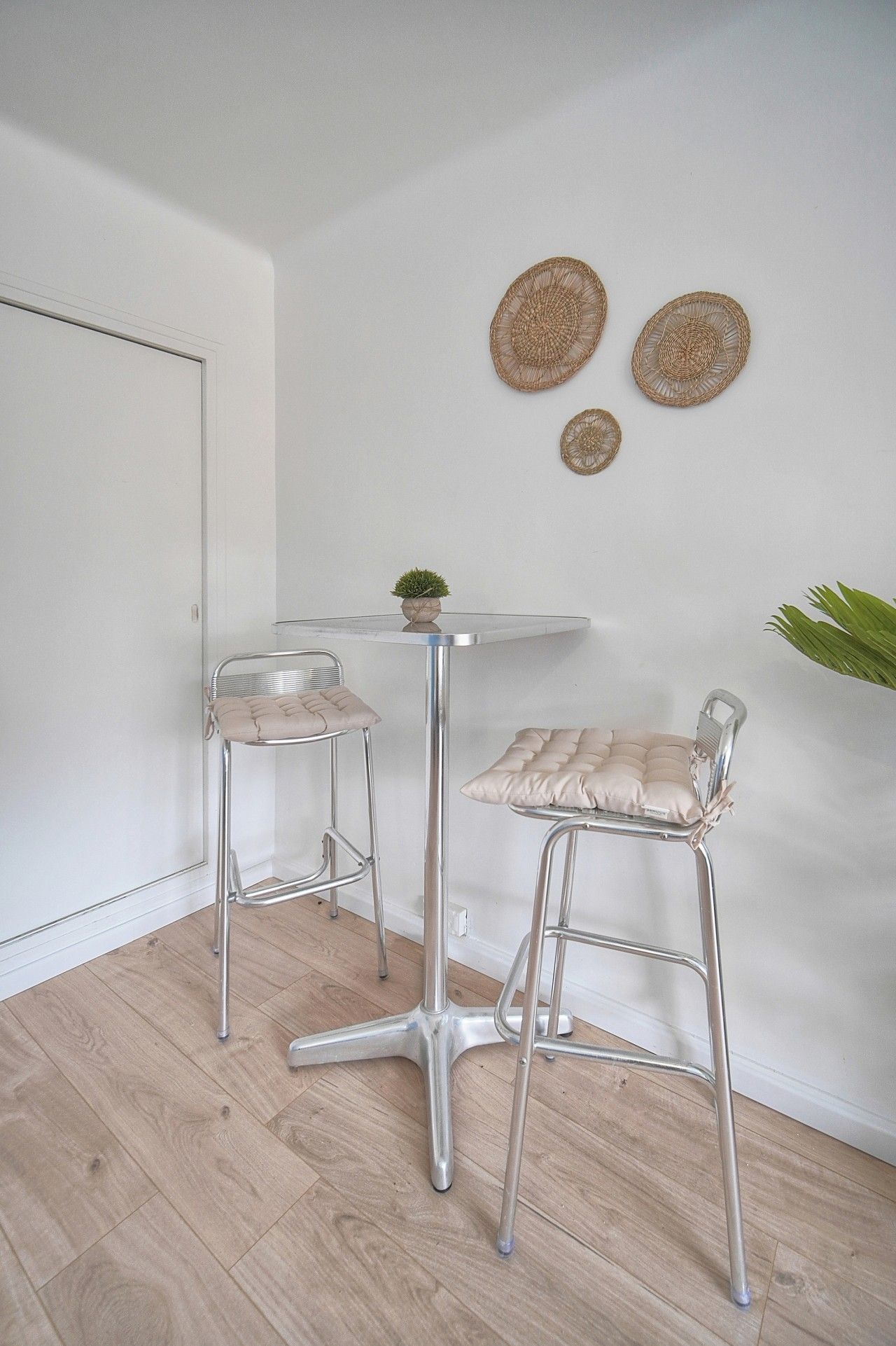 A modern room with two metal bar stools, a small table, and a potted plant.