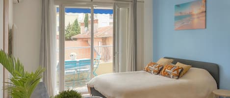 Un dormitorio con cama, una mesita de noche, una planta en maceta y vistas al exterior.