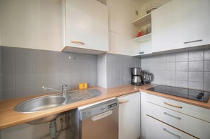 Eine kleine Küche mit Spüle, Geschirrspüler und Kaffeemaschine.