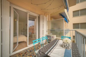 Ein Balkon mit Esstisch, Stühlen und einem Ventilator.