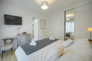Ein Schlafzimmer mit Bett, Kommode, Fernseher und Spiegel.
