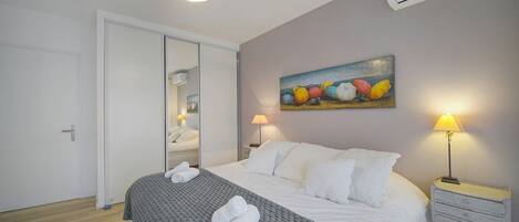 Une chambre d’hôtel avec un lit, des lampes de chevet, un tableau et un appareil de climatisation.