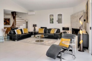 A modern living room with a sectional sofa, a glass coffee table, and a fireplace. - Four-bedroom home in France, Vallauris (Vallauris)