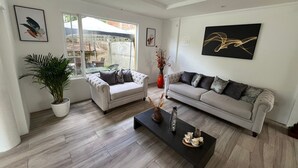 A living room with two sofas, a coffee table, a potted plant, and artwork on the walls. - Hotel Arupo Residence Aeropuerto (Tababela)