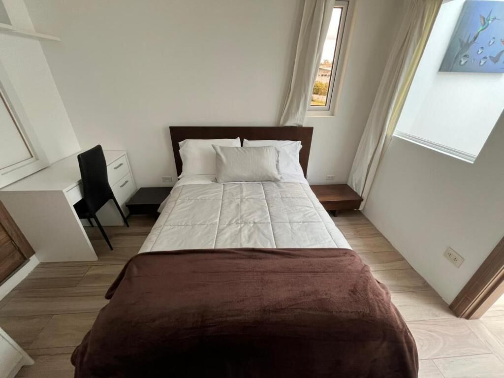 A bedroom with a bed, a desk, and a chair.