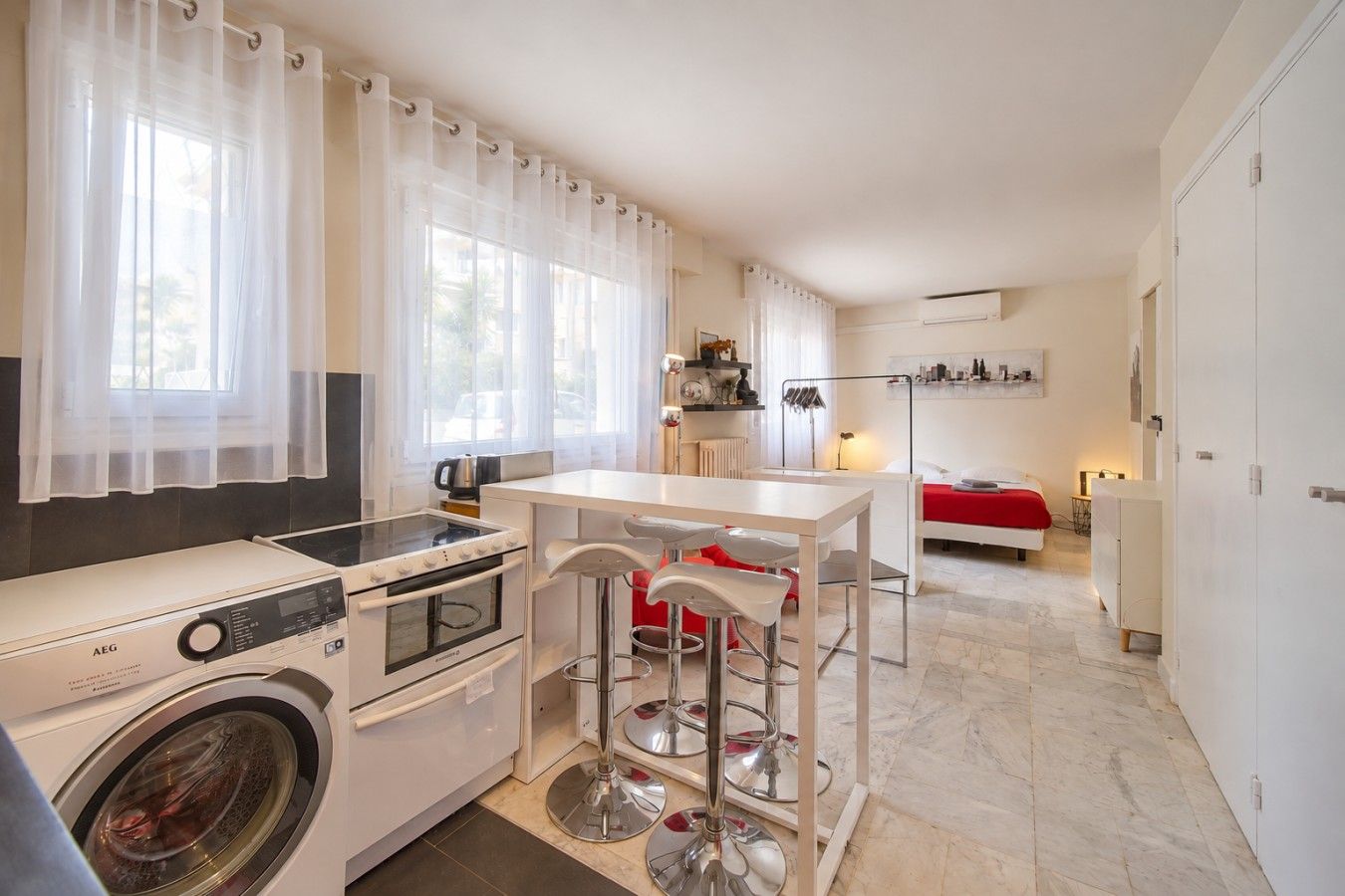 Habitación de hotel pequeña con kitchenette, cama y un rincón de comedor.