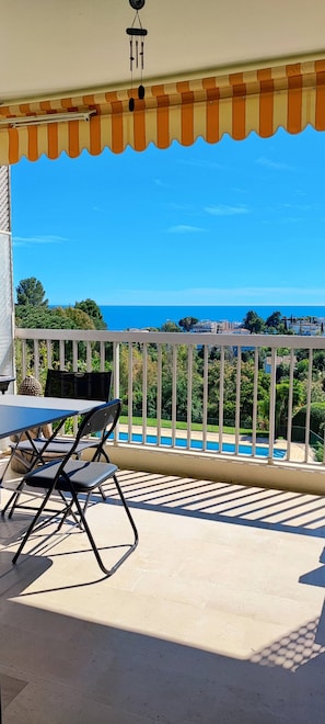 Ein Balkon mit Blick auf ein Schwimmbecken und das Meer.