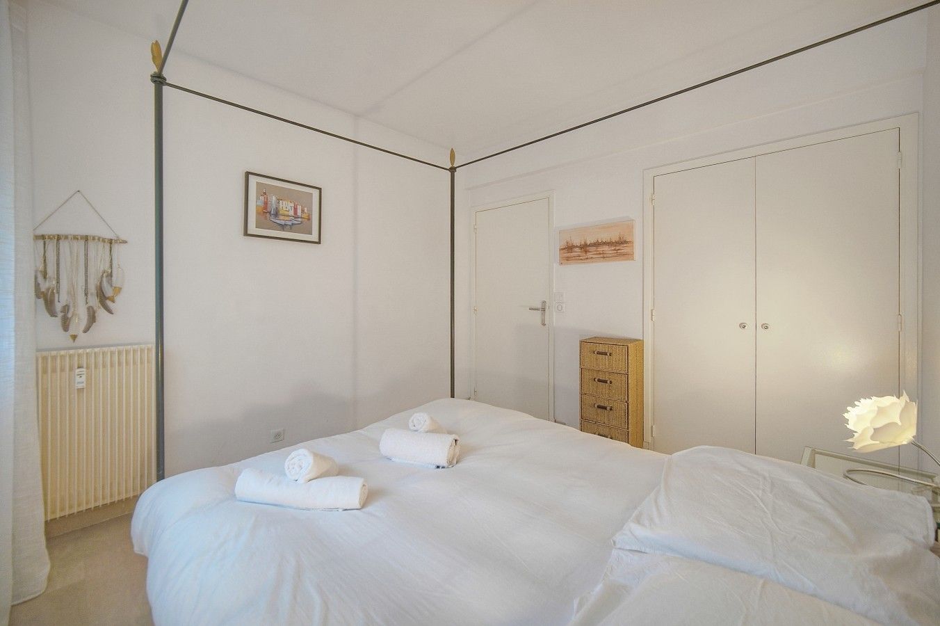 A bedroom with a bed, a dresser, a radiator, and a wall-mounted picture.