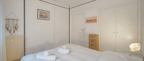 A bedroom with a bed, a dresser, a radiator, and a wall-mounted picture.