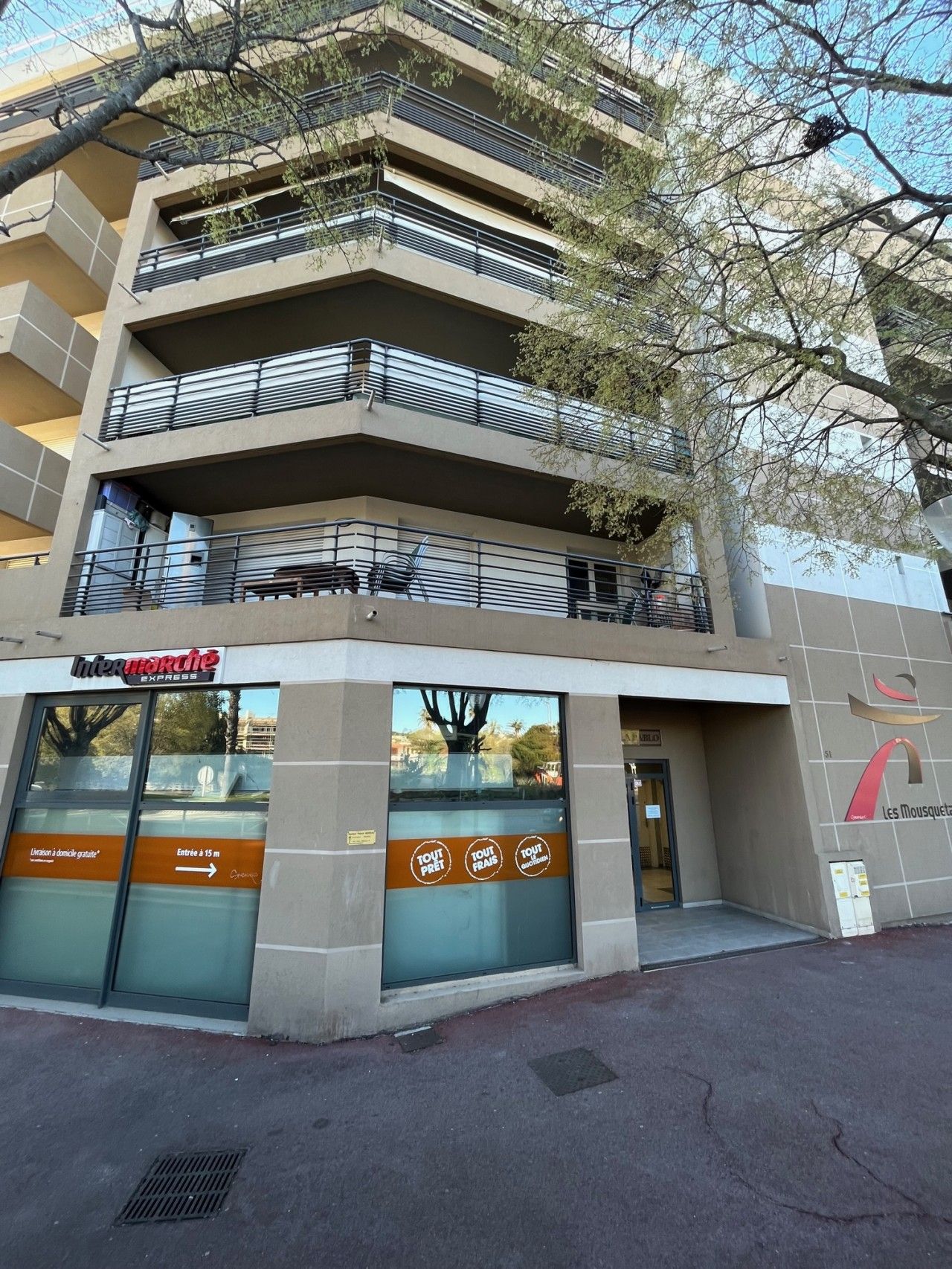 A multi-story building with a storefront labeled 'Intermarché Express' and a sign indicating 'Tout Prêt' (Everything Ready).