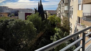 Un edificio residencial con balcones, cielo despejado y vegetación circundante.