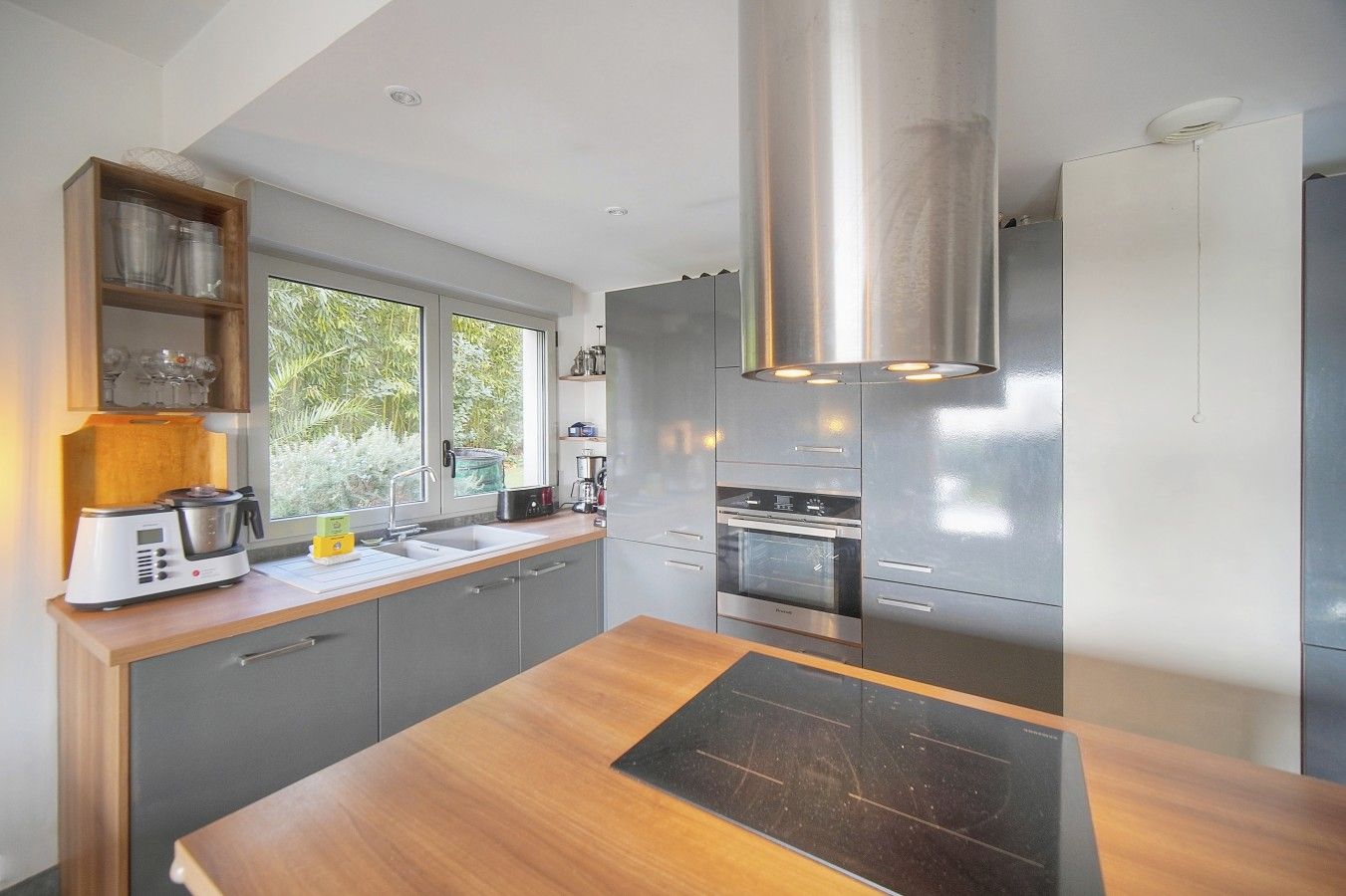 A modern kitchen with a wooden countertop, stainless steel appliances, and a window providing natural light.