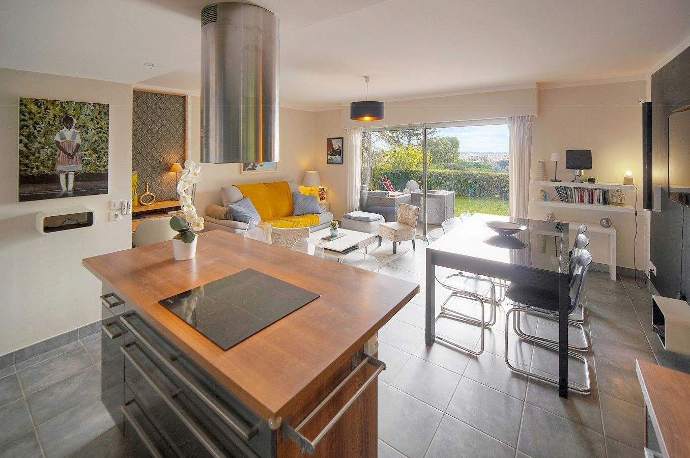 A modern kitchen with a central island, dining area with chairs, and a living space with a sofa and coffee table.